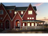 Charming home with red siding, covered porch, and well-manicured landscaping at twilight at 18028 French Creek Ave, Parker, CO 80134