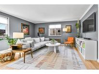 Bright living room features a comfortable gray sofa, unique décor, large window and hardwood floors at 85 N Ogden St # 13, Denver, CO 80218