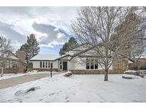 Snow-covered front yard of a remodeled midcentury modern home at 2133 S Parfet Dr, Lakewood, CO 80227