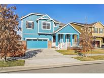 Charming blue two-story home with a front porch, blue garage door, and manicured landscaping at 786 Sundance Ln, Erie, CO 80516