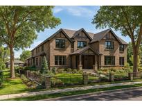 Charming two-story home with a brick facade, manicured lawn and a beautiful garden area surrounded by a wrought iron fence at 343 S Gaylord St, Denver, CO 80209
