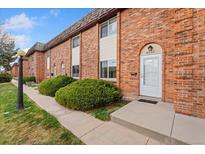 Brick townhome featuring manicured landscaping, private entrance, and well-maintained exterior at 4555 S Lowell Blvd, Denver, CO 80236