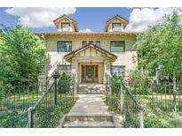 Brick two-story house with a classic design, landscaped yard, and a metal fence at 1827 N Bellaire St, Denver, CO 80220