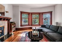 Sunlit living room features hardwood floors, a fireplace, and a bay window providing ample natural light at 836 E 17Th Ave # 2E, Denver, CO 80218