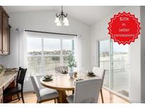 Bright dining area featuring a round wooden table, scenic views, and modern lighting fixtures at 8802 E 148Th Ln, Thornton, CO 80602