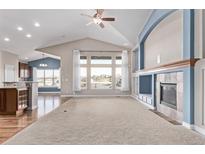 Spacious living room with vaulted ceilings, fireplace, and natural light from large windows at 8802 E 148Th Ln, Thornton, CO 80602