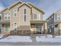 Two-story townhome with light beige siding, stone accents, and a covered front porch at 17991 E 103Rd Ave, Commerce City, CO 80022