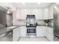 Well-lit kitchen with stainless steel appliances, undermount sink, gray countertops and white cabinets at 2645 S Xanadu Way # D, Aurora, CO 80014