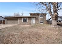 Split level home with a 2-car garage and muted brown siding under a blue sky at 15650 E Eldorado Dr, Aurora, CO 80013
