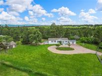 Sprawling property featuring a charming home, lush green lawn, circular driveway, and mature trees at 652 Verdos Dr, Elizabeth, CO 80107