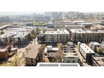An aerial view showcases a city neighborhood featuring modern apartments, solar panels and city skyline in the background at 1749 Boulder St, Denver, CO 80211