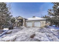 Snow covered home exterior, three-car garage, and landscaping at 20434 Kenneth Lainer Dr, Monument, CO 80132