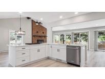 Bright kitchen boasts white cabinetry, quartz countertops, stainless steel appliances, and a brick fireplace feature at 10506 Brown Fox Trl, Littleton, CO 80125