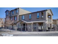 Inviting exterior view of a multi-story townhome featuring muted colors, a fenced front yard, and a charming covered porch at 10588 Parkington Ln # 39A, Highlands Ranch, CO 80126