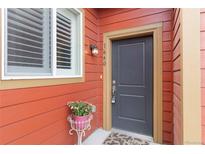 Charming entryway featuring a gray front door, red siding, and a delightful flower arrangement at 1640 Aspen Meadows Cir, Federal Heights, CO 80260