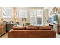 Inviting living room with a large, comfortable leather sofa and bright natural light from a sliding glass door at 1640 Aspen Meadows Cir, Federal Heights, CO 80260