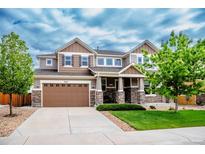 Inviting two-story home with a two car garage, stone accents, landscaped yard, and covered porch at 3421 E 143Rd Dr, Thornton, CO 80602