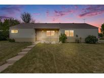 Charming single-story home with a well-manicured lawn at sunset with a classic covered front porch and large windows at 107 S Windsor Dr, Denver, CO 80219