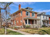 Charming two-story brick home featuring a covered front porch and a well-maintained front yard at 997 S Pearl St, Denver, CO 80209