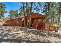 Charming two-story home with a front porch, landscaped yard, and mature trees on a sunny day at 767 Tenderfoot Dr, Larkspur, CO 80118