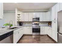 Bright kitchen features white cabinets, stainless steel appliances, and granite countertops at 9758 Laredo St # 1E, Commerce City, CO 80022