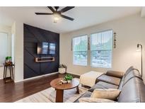 Cozy living room with hardwood floors, custom wall design, and a comfortable brown leather sectional at 9758 Laredo St # 1E, Commerce City, CO 80022