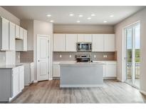 Bright kitchen features white cabinets, stainless steel appliances and a center island at 4255 Gozzer Ranch Dr, Elizabeth, CO 80107