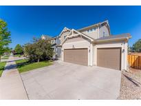 Charming home with a two-car garage and a well-maintained lawn on a beautiful sunny day at 10569 Racine St, Commerce City, CO 80022