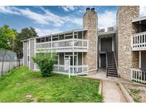 Condo exterior with gray siding, stone accents, and a well-maintained green lawn at 18103 E Kentucky Ave # 103, Aurora, CO 80017
