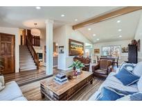 Cozy living room featuring hardwood floors, a vaulted ceiling, a staircase, and leather armchairs, creating a welcoming atmosphere at 11892 Vallejo St, Denver, CO 80234