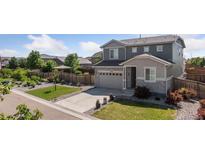 Charming two-story home features a manicured lawn, stone accents, and a spacious driveway leading to an attached garage at 25106 E 1St Ave, Aurora, CO 80018