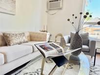 Bright living room features stylish furniture, decor, and a glass coffee table at 1050 N Lafayette St # 408, Denver, CO 80218