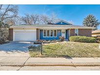 Charming single-story home with a well-manicured lawn, brick accents, and attached garage at 1701 S Newport Way, Denver, CO 80224