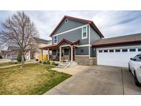 Charming two-story home featuring a well-maintained lawn, covered porch, and attached two-car garage at 1824 Asoka St, Strasburg, CO 80136