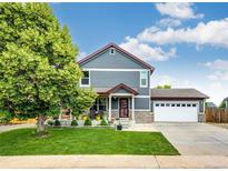 Charming two-story home with well-manicured lawn, attached garage, and covered front porch at 1824 Asoka St, Strasburg, CO 80136
