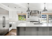 Bright, modern kitchen with stainless steel appliances, white cabinetry, and a large center island at 39 Sedgwick Dr, Cherry Hills Village, CO 80113
