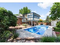 Backyard view featuring a sparkling blue pool, surrounded by a patio and lush landscaping at 10520 W 101St Pl, Westminster, CO 80021