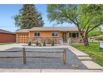 Charming single-story home showcasing a stone facade, orange trim, and well-maintained landscaping at 3107 S Wolff St, Denver, CO 80236
