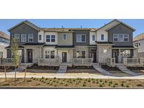 Modern townhome featuring varied neutral exterior color, stone accents, and inviting front porches at 712 N Bently St, Watkins, CO 80137