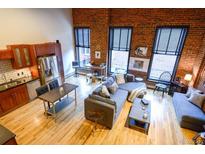 Spacious living room boasting exposed brick, hardwood floors, and large windows providing ample natural light at 1450 Wynkoop St # 3F, Denver, CO 80202