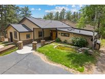 Stunning home with stone pillars, pond and lush landscaping, located on a beautiful large lot at 32173 Soda Creek Dr, Evergreen, CO 80439