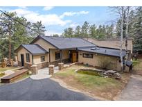 Charming exterior view showcasing the lush landscaping and unique architecture of this inviting home at 32173 Soda Creek Dr, Evergreen, CO 80439