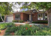 Charming brick home featuring well-maintained landscaping with vibrant flowers and a covered front entry at 12377 E Harvard Dr, Aurora, CO 80014