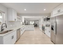 Spacious, renovated kitchen with stainless steel appliances, light wood floors, and white cabinets at 7752 Meade St, Westminster, CO 80030