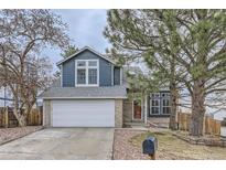 Charming home featuring blue siding, brick accents, an attached garage, and a well-maintained front yard at 9902 Independence St, Broomfield, CO 80021