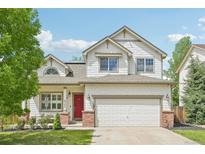 Charming two-story home with a red front door, a well-maintained lawn and a two car garage at 3745 Balderas St, Brighton, CO 80601