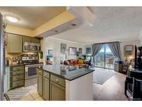 Bright open floor plan features a modern kitchen and cozy living area with stunning balcony views at 1301 Speer Blvd # 702, Denver, CO 80204