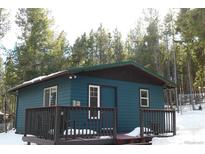 Quaint blue cabin with a deck, nestled in a snowy forest setting at 28 Deer Rd, Evergreen, CO 80439