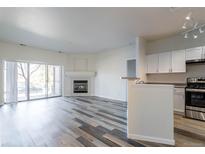 Bright living room with fireplace, wood-look flooring, and sliding glass doors to an outdoor space at 7414 S Alkire St # 101, Littleton, CO 80127