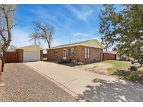 Charming brick home featuring a detached garage and spacious driveway at 902 Pacific Pl, Fort Lupton, CO 80621